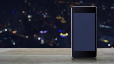 Modern akıllı cep telefonu ekranında çalma tuşu ahşap masa üzerinde bulanık gece lambası şehir kulesi ve gökdelen, iş müziği online konsepti