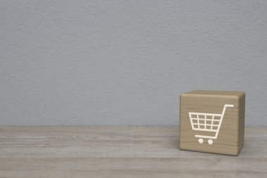 Alışveriş arabası düz simge blok küp beyaz duvar arkaplan üzerinde ahşap masa, atölye online konsept