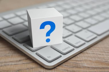 Tahta masadaki modern bilgisayar klavyesi, iş dünyası müşteri hizmetleri ve çevrimiçi konsepti destekleyen beyaz blok küpündeki soru işareti simgesi düz simgesi