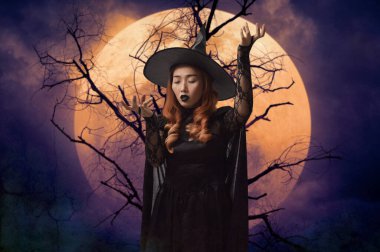 Ölü ağacın üzerinde duran gizemli cadılar bayramı cadısı dolunay ve ürkütücü bulutlu gökyüzü, Cadılar Bayramı gizemi kavramı