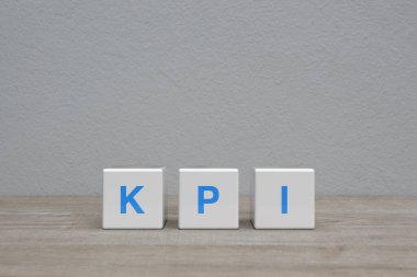 KPI letter on white block cubes on wooden table over white wall background, Key Performance Indicator business target concept