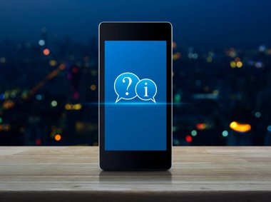 Soru işareti ve bilgi sohbet simgesi ahşap masadaki akıllı cep telefonu ekranında bulanık renkli şehir kulesi ve gökdelen, iş dünyası müşteri hizmetleri ve çevrimiçi konsept desteği üzerinde