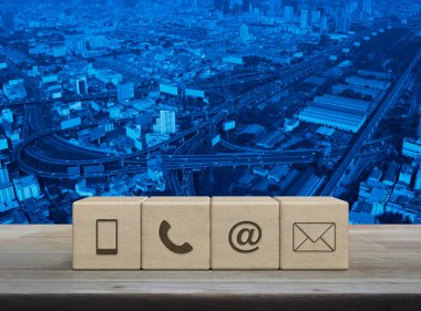 Cep telefonu, telefon, e-posta adresi, posta simgesi blok küpleri üzerinde ahşap masa üzerinde modern ofis kulesi, sokak, ekspres yol ve gökdelen, iş dünyası müşteri hizmetleri ve çevrimiçi konsept desteği