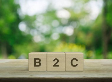 B2C letter on block cubes on wooden table over blur green tree in park, Business to customer marketing and strategy concept