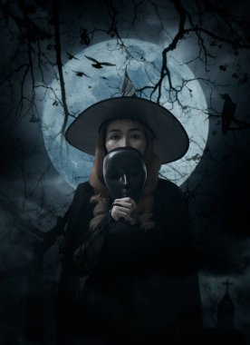 Cadılar Bayramı cadısı elinde siyah maske, kilise, karga, kuşlar, ölü ağaç, dolunay ve bulutlu gökyüzü, Cadılar Bayramı gizemi