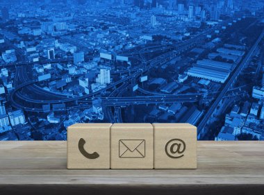 Telefon, e-posta, e-posta ikonu modern şehir kulesi, sokak, gökdelen, iş dünyası müşteri hizmetleri ve çevrimiçi konsept üzerinde ahşap masa üzerinde
