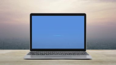 Modern dizüstü bilgisayar ekranındaki düz ikon şehir kulesinin üzerindeki ahşap masada ve günbatımında gökdelen, klasik tarzda, iş bankacılığı online konsepti