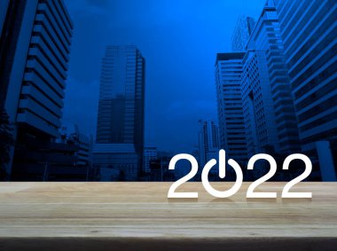 2022 Modern ofis kulesi ve gökdelen üzerinde ahşap masa üzerinde işletme düz ikonu kurun, Mutlu yıllar 2022 kapak konsepti