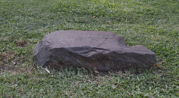 Pedra vermelha na grama verde — Fotografia de Stock