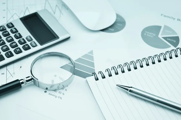 Bok, förstoringsglas, penna och kalkylator på finansiella diagram en — Stockfoto
