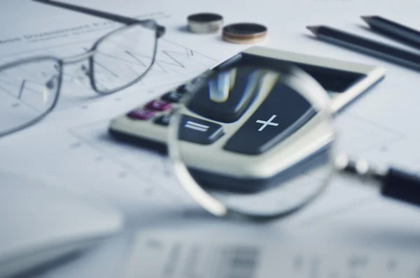 Calculator button plus and magnifying glass on graph paper — Stock Photo, Image