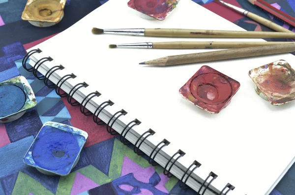 Used water color paint, pencil and paintbrush on white book — Stock Photo, Image