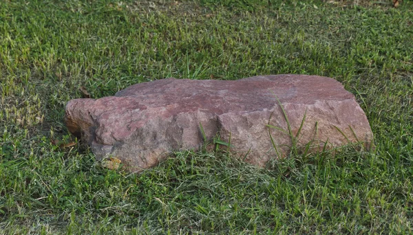 Pedra vermelha na grama verde — Fotografia de Stock