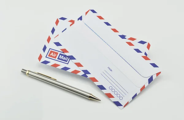 Stack of air mail envelopes with pen on white background — Stock Photo, Image