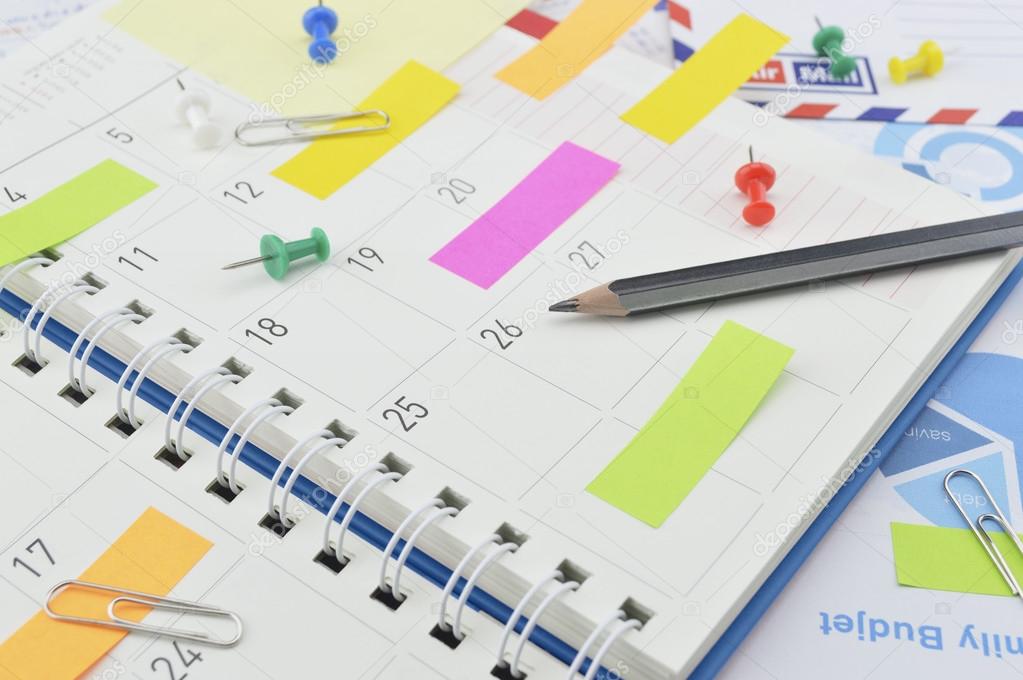 Pencil with post It notes and pin on business diary page