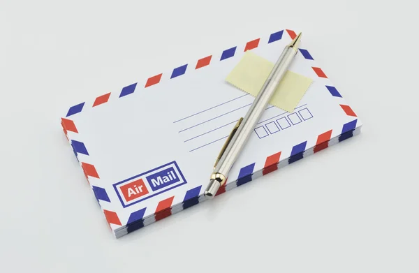 Stack of air mail envelopes with pen and stamp on white — Stock Photo, Image