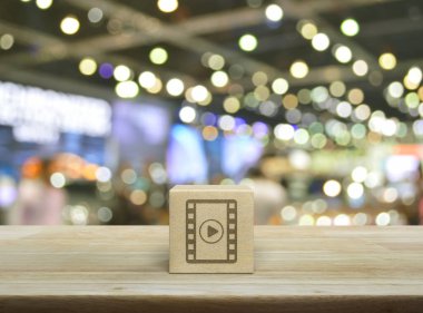 Tahta kübün üzerinde film yassı ikonu, bulanık ışık ve alışveriş merkezinin gölgesi üzerine tahta masa, iş sineması çevrimiçi konsepti.