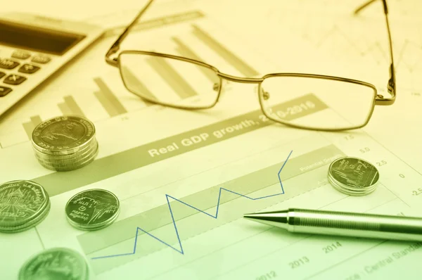 Glasses, pen and coin on growth financial graph — Stock Photo, Image
