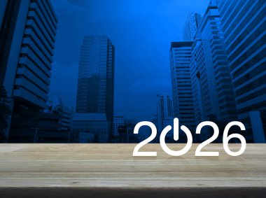 2026, modern ofis kulesi ve gökdelenin üzerindeki ahşap masa üzerinde yeni iş ikonu oluşturun. Mutlu yıllar 2026 başarı konsepti.