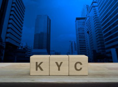 KYC kısaltma harfleri ahşap küpler üzerinde ahşap masa üzerinde modern ofis kulesi ve gökdelen üzerinde, Müşteri kavramını biliyorum