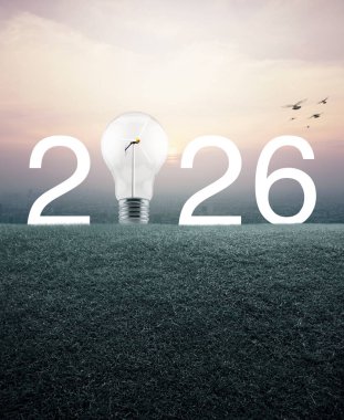 2026 beyaz yazı ve ampul, içinde rüzgar türbini olan yeşil çimen tarlasında günbatımında şehir manzarası, klasik tarzda, mutlu yeni yıl ekolojik kapak konsepti.