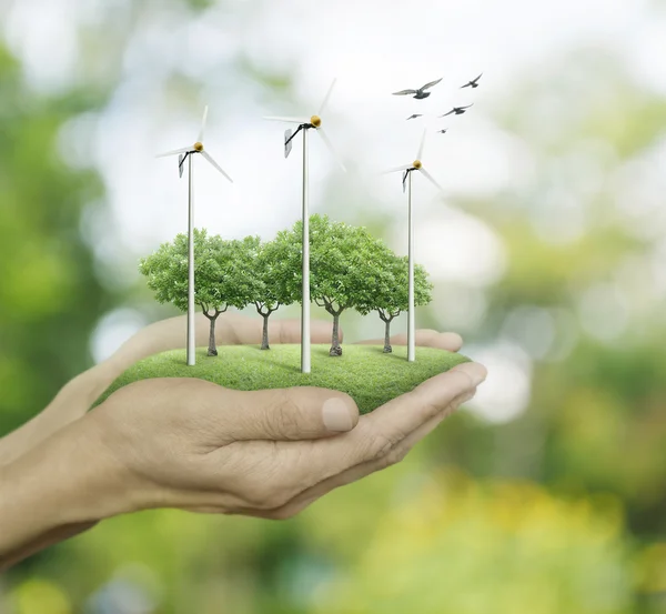 Wind turbines and trees on hands over green bokeh background, Ec — Stock Photo, Image