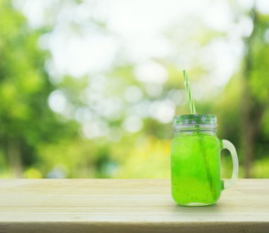 Yeşil buz içki ve saman üzerinde ahşap masa üzerinde yeşil bo kavanoz