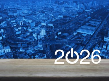 2026 Modern şehir kulesi, sokak, ekspres yol ve gökdelen üzerinde ahşap masa üzerinde işletme ikonu kurun. Mutlu yıllar 2026 başarı konsepti.