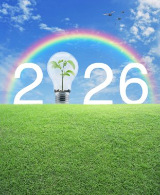2026 beyaz yazı ve ampul içinde yeşil çimlerin üzerinde gökkuşağı üzerinde küçük bir ağaç, kuşlar ve mavi gökyüzü beyaz bulutlar ile mutlu yıllar 2026 yeşil ekoloji ve tasarruf enerji kavramı