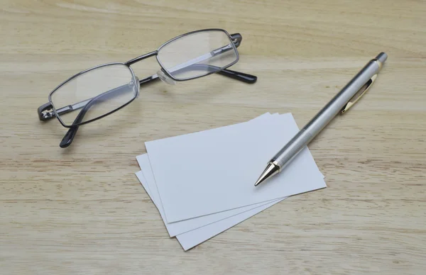 Blank business card with pencil and glasses on wooden table Stock Image