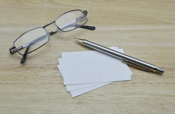 Tarjeta de visita en blanco con lápiz y vasos sobre mesa de madera — Foto de Stock