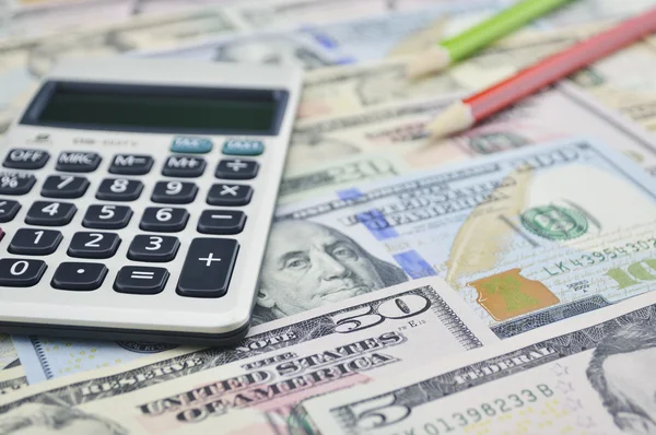 Miniräknare och penna på dollar sedel pengar — Stockfoto