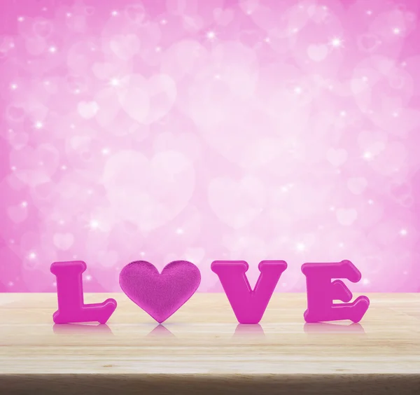 Pink love alphabet and fabric heart on wooden table over light p — Stock Photo, Image