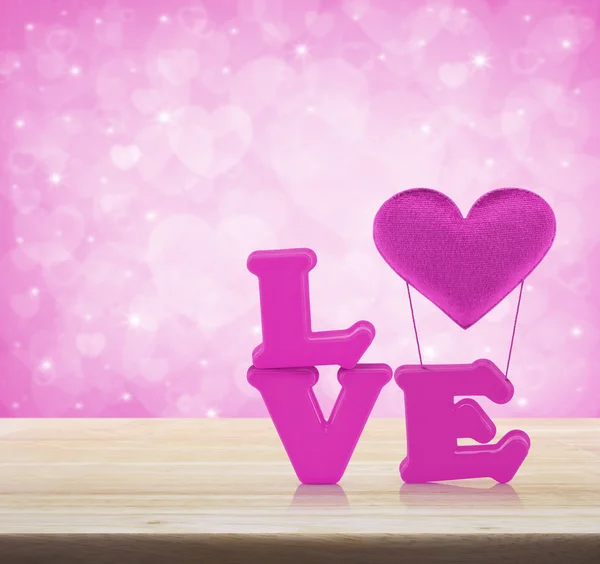 Pink love alphabet and fabric heart on wooden table over light p — Stock Photo, Image