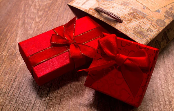 木製の背景にクラフトギフトバッグに2つの包装プレゼント 赤いリボンの弓で結ばれた長方形の赤いギフトボックス 休日のコンセプト バレンタインデーだ ショッピング販売 — ストック写真