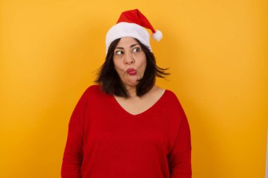 Orta yaşlı, komik bir Arap kadın Noel şapkası takıyor, gözlerini şaşı yapıyor, dudaklarını buruşturuyor, bütün gün ders çalıştıktan sonra aptallık yapıyor.. 