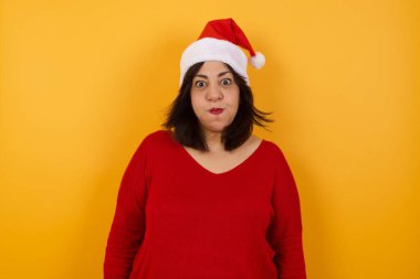 Güzel, orta yaşlı, Noel şapkası takan, komik yüzlü bir Arap kadın. Havayla şişmiş ağız, çılgın bir ifade..