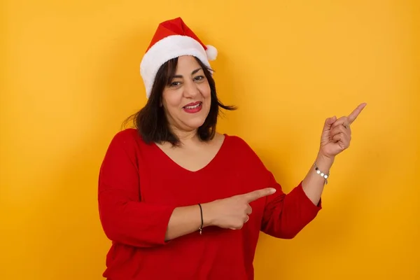 Werbekonzept Positive Hübsche Arabische Frau Mittleren Alters Mit Weihnachtsmütze Und — Stockfoto