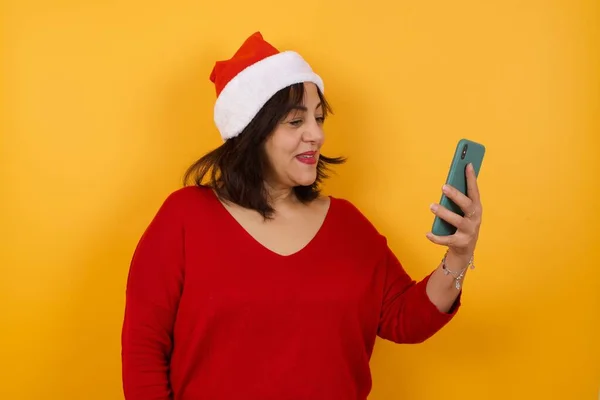 Foto Einer Fröhlichen Arabischen Frau Mittleren Alters Mit Weihnachtsmütze Macht — Stockfoto