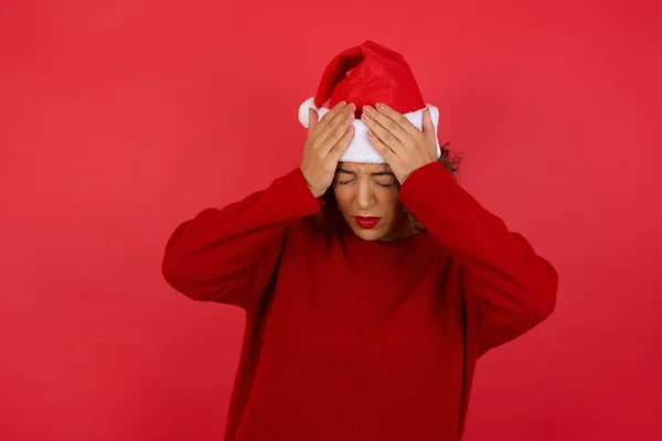 Joven Hermosa Mujer Con Sombrero Navidad Sosteniendo Cabeza Sobre Fondo —  Fotos de Stock