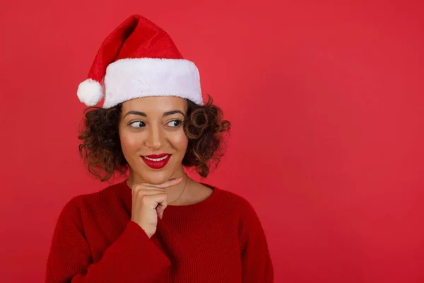 Verträumte Frau Mit Weihnachtsmütze Und Rotem Pullover Mit Angenehmem Gesichtsausdruck — Stockfoto