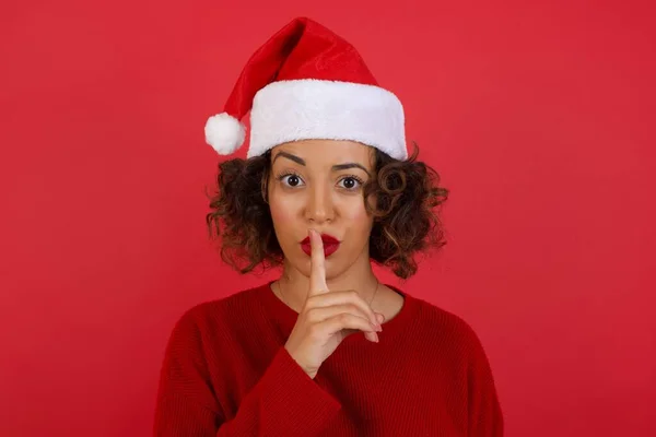 Emotional Überraschte Frau Mit Weihnachtsmütze Und Rotem Pullover Macht Schweigegegeste — Stockfoto