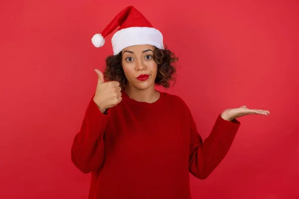 Jonge Vrolijke Vrolijke Vrouw Met Kerstmuts Rode Trui Met Duim — Stockfoto