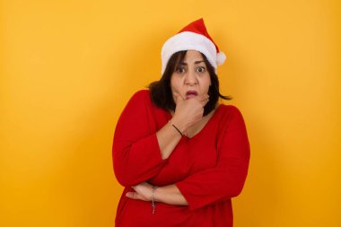 Endişe. Orta yaşlı, Noel şapkası takan, elleri kapalı ve evde dikilen güzel bir Arap kadının kavramsal görüntüsü. Bir şeyden ya da birinin çivi yemesinden korktun mu?