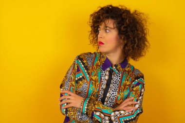 Renkli gömlek giyen üzgün bir Arap kadını kolları çaprazlanmış bir şekilde içeride hayal ediyorum. Kötü haberleri dinledikten sonra hayal kırıklığına uğramış bir ifadeyle bakıyorum. Kendine güvenen kız..