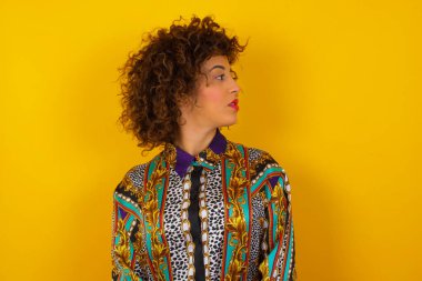 Stüdyo duvarından izole edilmiş renkli gömlek giyen ciddi bir Arap kadının profili. 