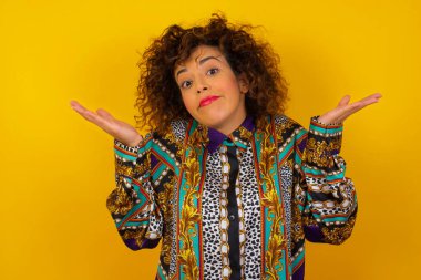 Belki evet ya da hayır. Şaşkınlık içinde renkli gömlek giyen şüpheli bir Arap kadın omuz silkiyor, duvarın arkasında neyi izole etmek istediğine karar vermeye çalışıyor. Tereddüt ve belirsizlik.