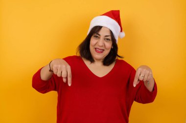 Doğru kızı buldun, beni seç. Kendinden emin, kendinden emin ve karizmatik orta yaşlı kadın Noel şapkası takıyor. Kendini büyük bir gülümseme ve vücuduna işaret eden bir rol istiyormuş gibi tanıtıyor.