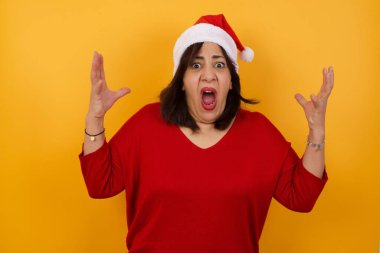 Çığlık, nefret, öfke. Duygusal Arap orta yaşlı kadın Noel şapkası takıyor ve bağırıyor.