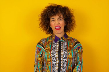 Vücut dili. Yüzü asık, rengarenk gömlekler giyen, bir şeye karşı hoşnutsuzluk gösteren, stresli Arap kadın..